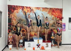 Five gymnasts on fall competition podium