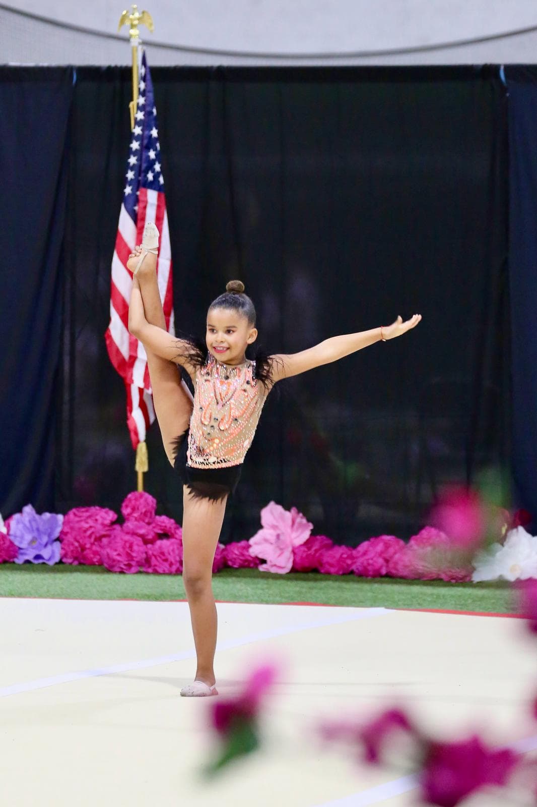 Young gymnast performing vertical split by American flag