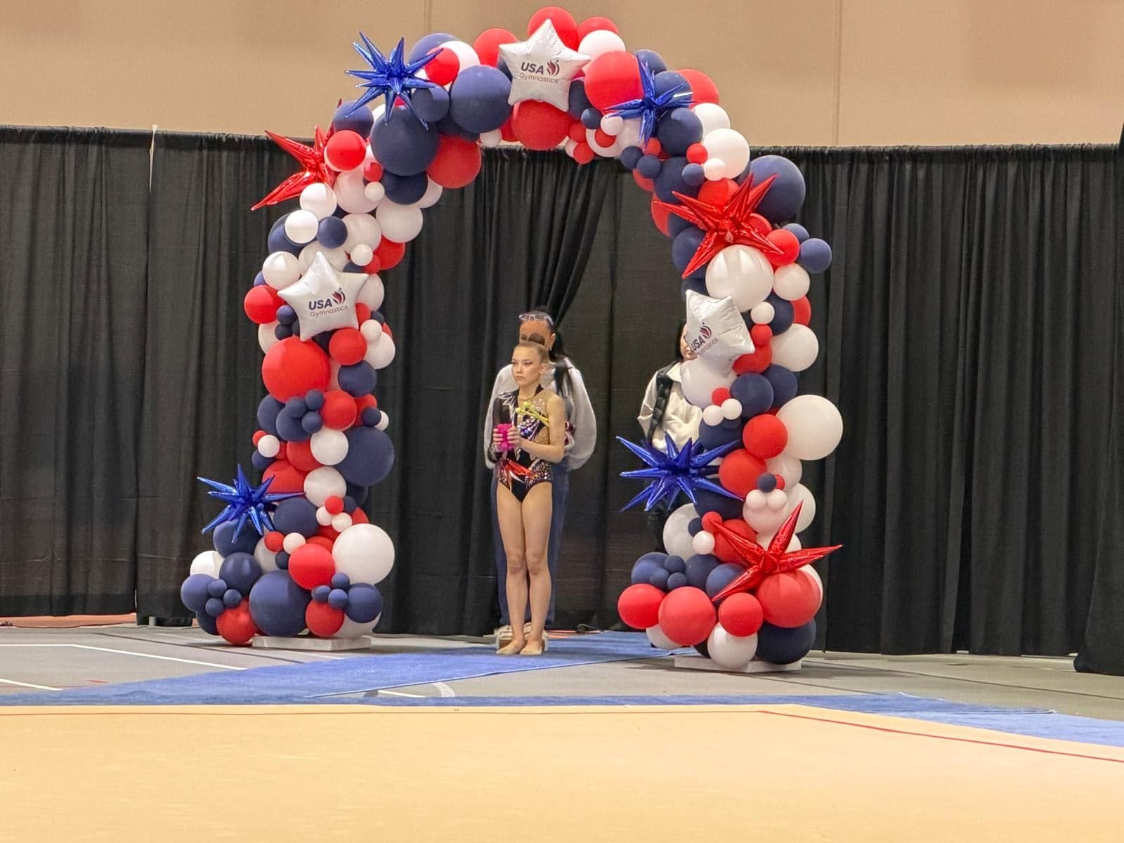 Young RRT athlete inside the USA Gymnastics balloon arch at the 2026 Rhythmic Elite Qualifier