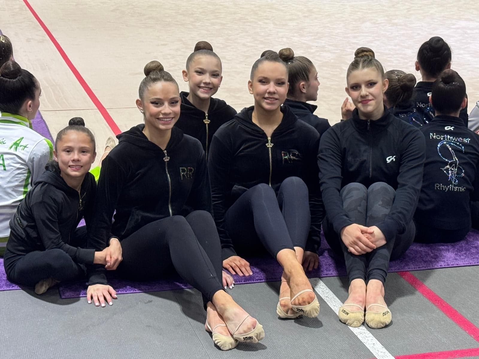 RRT team in matching tracksuits on the competition floor at the 2026 USAG Rhythmic Elite Qualifier