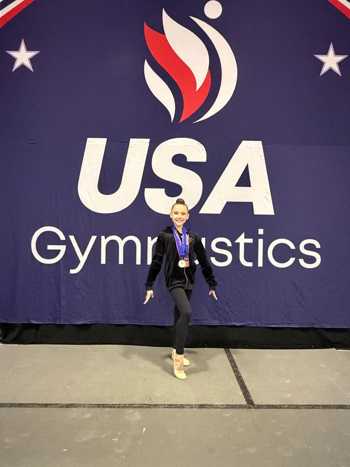 RRT athlete posing in front of the USA Gymnastics backdrop at the 2026 Rhythmic Elite Qualifier