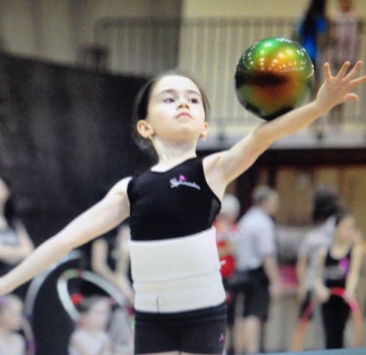Young gymnast tossing ball at competition