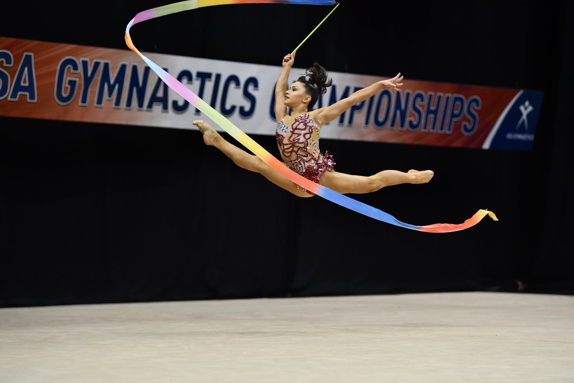 Gymnast performing split leap with ribbon at USA Gymnastics Championships