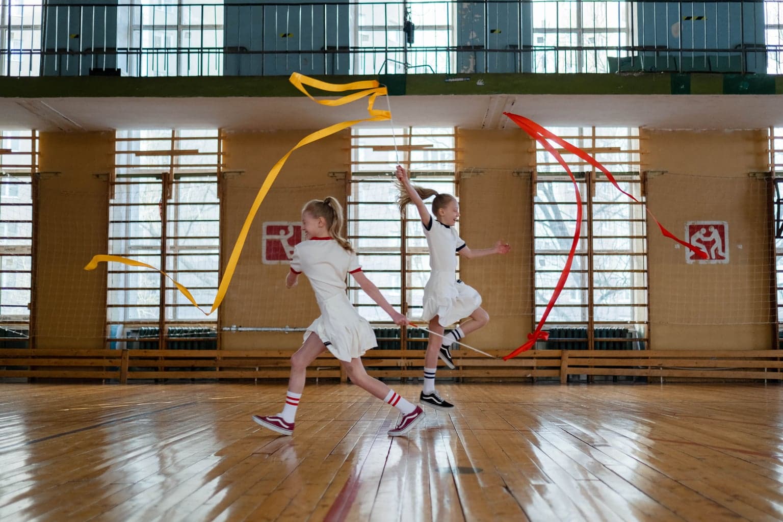 Two children running with ribbons in a school gym